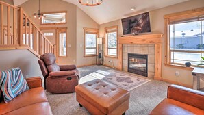 A spacious living room with a fireplace, leather sofas, and a staircase. - Family-friendly Oregon Vacation Home w/ Yard (Bend)