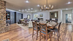 A spacious living area with a stone fireplace, a dining table set for six, and a large sofa. - Beautiful Ranch Home w/ Cascade Mountain View (Powell Butte)