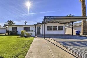 A single-story house with a covered patio, a well-maintained lawn, and a clear sky.