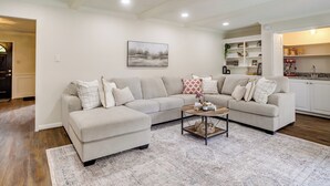 A living room with a beige sectional sofa, a coffee table, and a patterned rug.