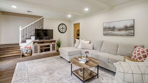 A living room with a sofa, coffee table, TV, and a staircase.