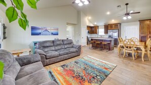 Un salon spacieux avec un canapé gris, un tapis coloré et un ventilateur de plafond.