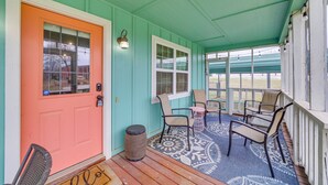 Une véranda avec un plafond de couleur turquoise, une porte orange vif et un tapis à motifs.