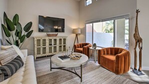 Een moderne woonkamer met een bank, twee fauteuils, een salontafel, een televisie, een kast en een girafssculptuur.
