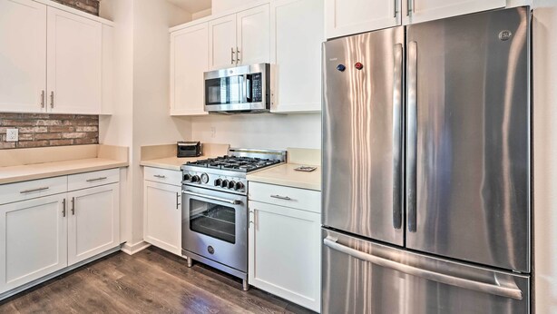 A modern kitchen with white cabinetry, a stainless steel refrigerator, a built-in oven, and a microwave.
