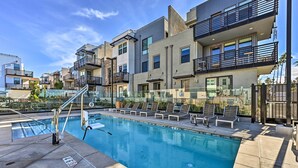 A modern residential building with a rooftop pool, outdoor seating, and a clear blue sky.