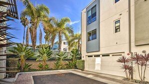 A modern building with a parking area, palm trees, and a clear sky.