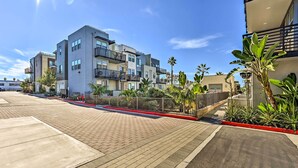 A modern multi-story residential building with balconies, paved walkways, and tropical landscaping.