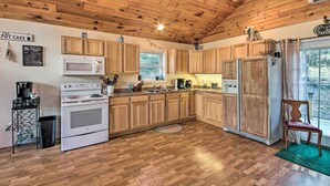 A kitchen with wooden cabinets, a microwave, a stove, and a refrigerator. - Stunning Monson Getaway on the Water! (Monson)