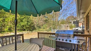 A deck with a grill, outdoor furniture, and a green umbrella.