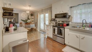 A kitchen with white cabinets, stainless steel appliances, and a wooden floor.