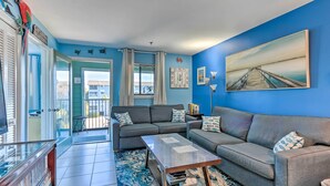 A living room with a grey sofa, a coffee table, and a painting on the wall.