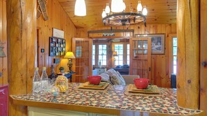 A wooden cabin interior with a kitchen area featuring a mosaic tile countertop, wooden cabinets, and a chandelier. - Lakefront Cabin w/ Private Dock & Fire Pit! (Minocqua)