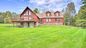 A two-story log cabin with a balcony, surrounded by a well-maintained lawn and trees. - Grand Windham Retreat w/ Fire Pit & Game Room (Windham)