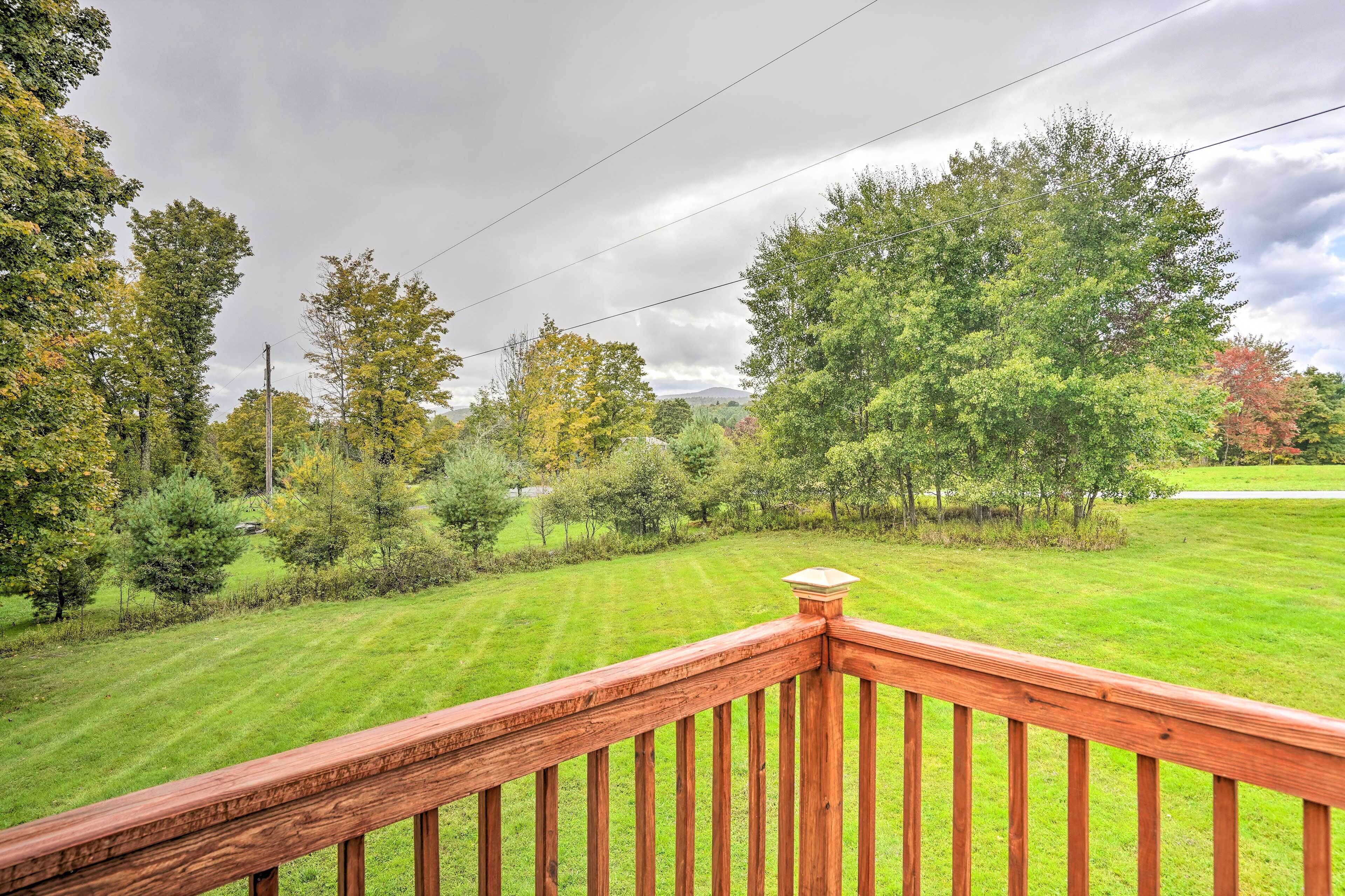 Une terrasse en bois offrant une vue sur une pelouse bien entretenue et des arbres.