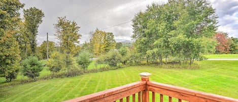 Une terrasse en bois offrant une vue sur une pelouse bien entretenue et des arbres.