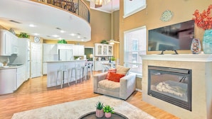 A spacious living area with a fireplace, a kitchen in the background, and a staircase leading to an upper level. - Beautiful Montgomery Home w/ Lakefront Deck! (Montgomery)
