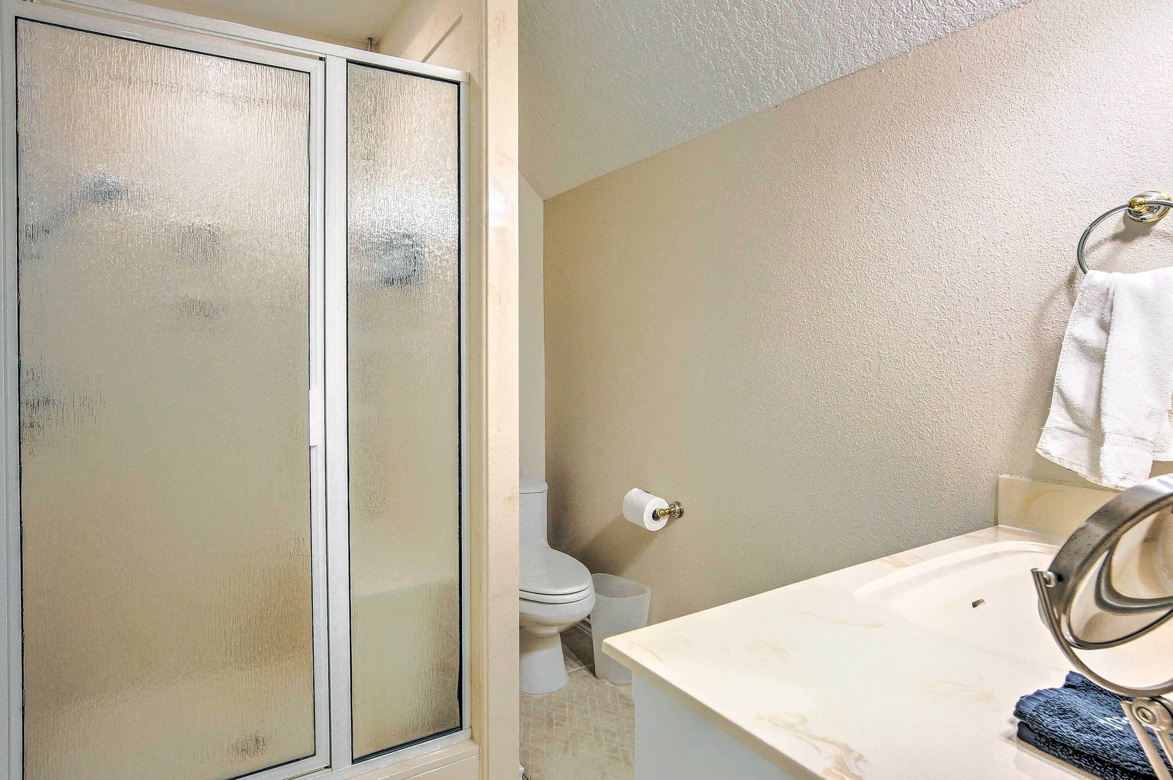 A bathroom with a shower enclosure, toilet, and sink.