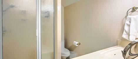 A bathroom with a shower enclosure, toilet, and sink.