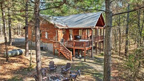 A rustic cabin with a deck, surrounded by trees.