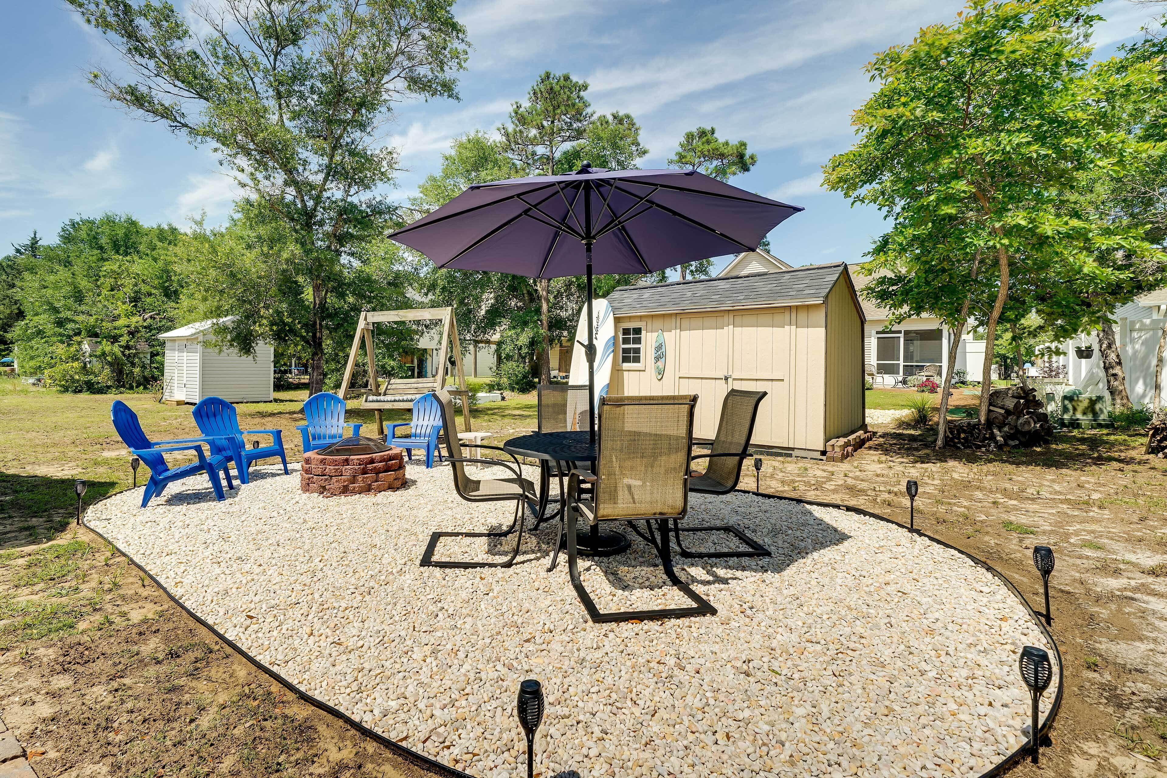 An outdoor patio with a table and chairs, a barbecue grill, and a large umbrella.