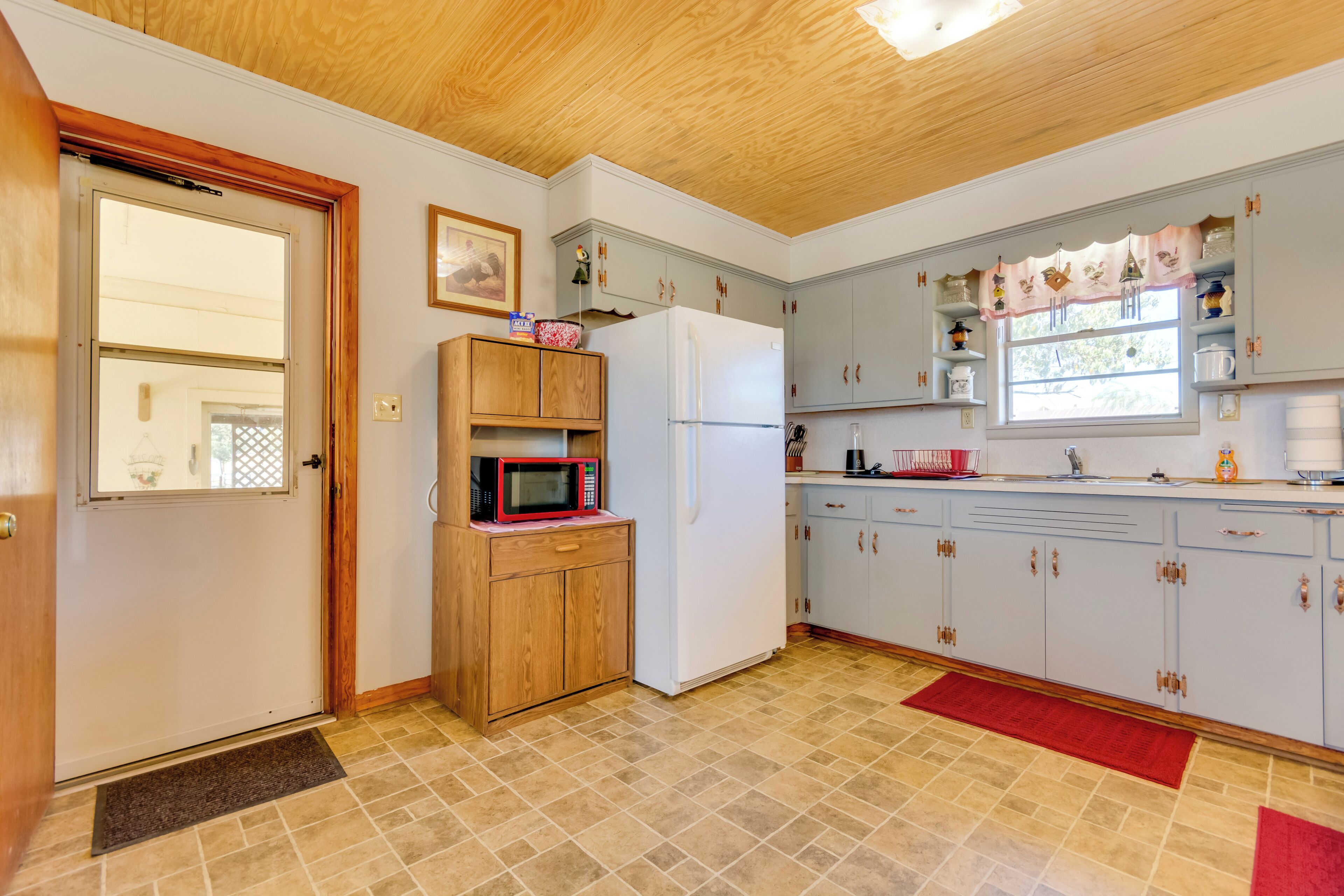 A kitchen with wooden cabinets, a white refrigerator, and a microwave on a wooden shelf.