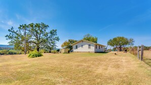 A single-story house with a front yard, a small tree, and a clear sky. - Charming Subiaco Getaway Near Arkansas River! (Subiaco)