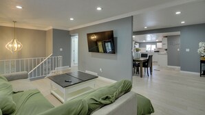 A modern living room with a sofa, coffee table, and a TV mounted on the wall. - Deck + Yard: Pet-friendly Apartment in Magna! (Magna)