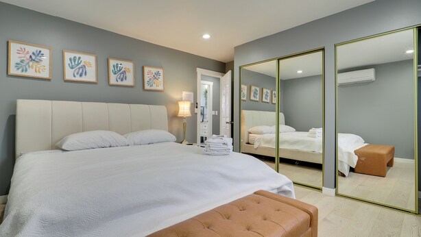 A modern bedroom with a large bed, a mirror, and artwork on the wall. - Deck + Yard: Pet-friendly Apartment in Magna! (Magna)