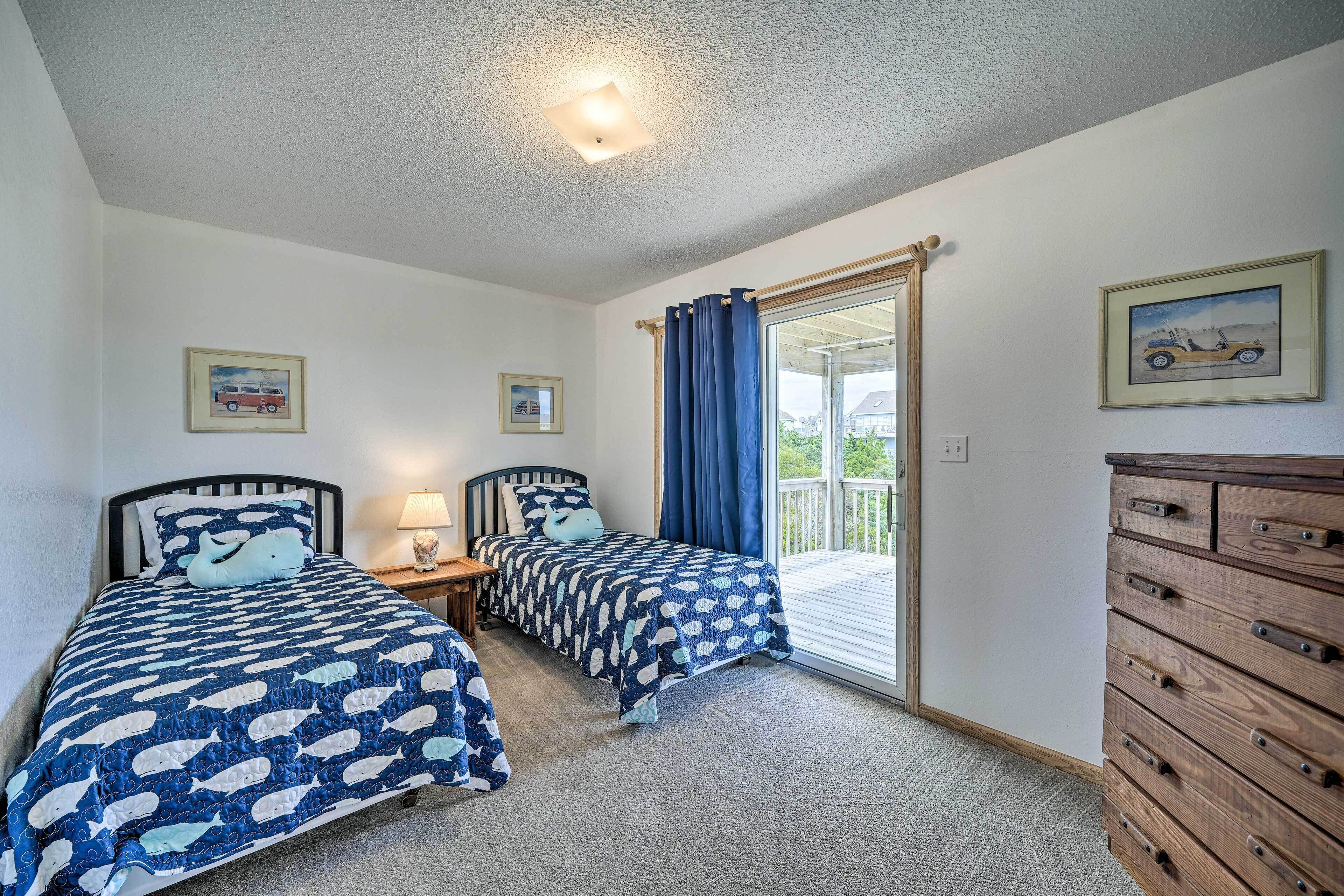A bedroom with two beds, a dresser, and a window with curtains.