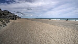 A beach with a wooden boardwalk, a sandy shore, and a cloudy sky. - Avon Home on the Channel w/ Deck & Views! (Avon)