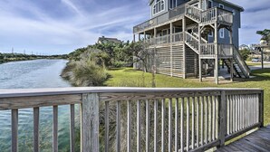 A waterfront house with a wooden deck and multiple levels. - Avon Home on the Channel w/ Deck & Views! (Avon)