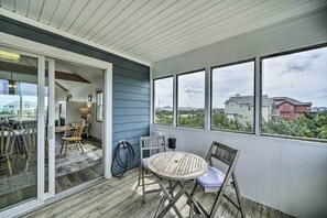 Une terrasse couverte avec une table et des chaises, une porte-fenêtre coulissante donnant sur l’intérieur, et une vue sur les maisons voisines.