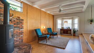A cozy living room with a fireplace, two chairs, a rug, and a ceiling fan.