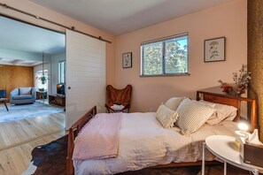 A bedroom with a bed, a chair, a bedside table, a window, and a door leading to another room. - < 3 Mi to Pearl St: Home w/ Large Yard in Boulder (Boulder)