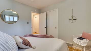 A bedroom with a bed, a chair, a mirror, and a door.