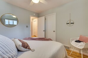 Une chambre à coucher avec un lit, une chaise, un miroir et une porte.