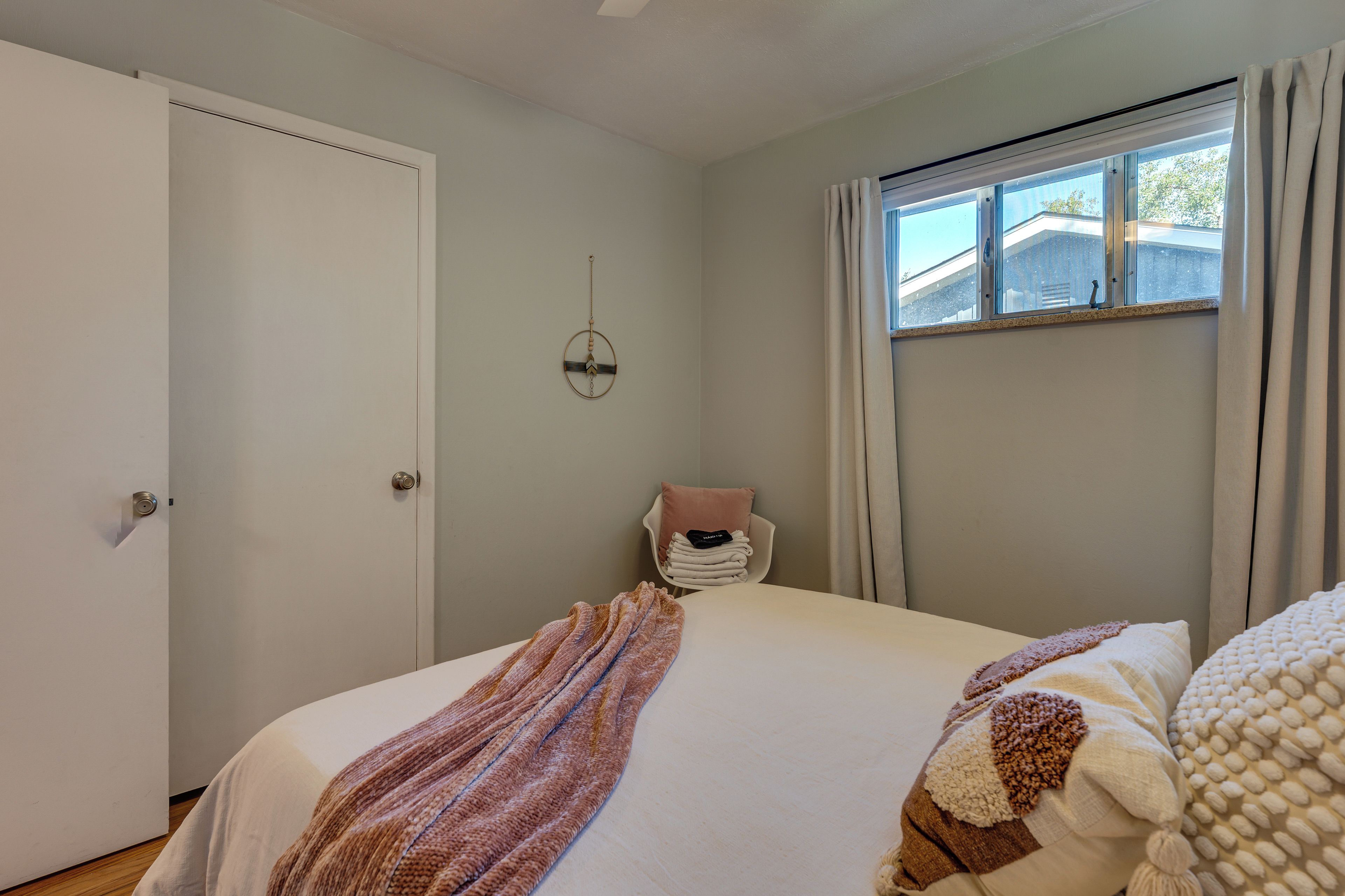 Une chambre à coucher avec un lit, une fenêtre avec des rideaux, une porte et un luminaire fixé au mur.
