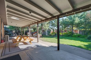 A covered patio area with a picnic table and a large window overlooking a backyard.