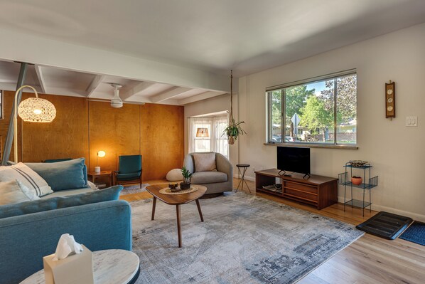 A modern living room with a sofa, armchair, coffee table, and a television.