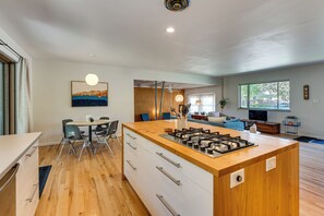 A modern kitchen with a central island, dining area with chairs, and a living room with a sofa and TV. - < 3 Mi to Pearl St: Home w/ Large Yard in Boulder (Boulder)