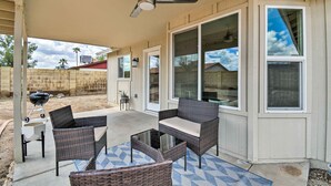 Ein überdachter Patio-Bereich mit Rattanmöbeln, einem Deckenventilator und einem Grill.