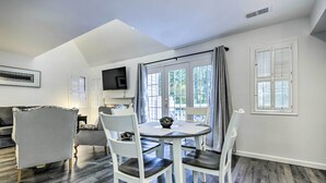 A dining area with a round table, white chairs, and a flat-screen TV mounted on the wall.