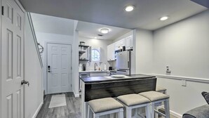 A modern kitchen with white cabinetry, a central island with stools, and recessed ceiling lights.