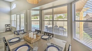 A dining area with a table set for four, large windows with blinds, and a wicker chandelier. - Private Pool & Fenced Yard: Phoenix Home (Phoenix)