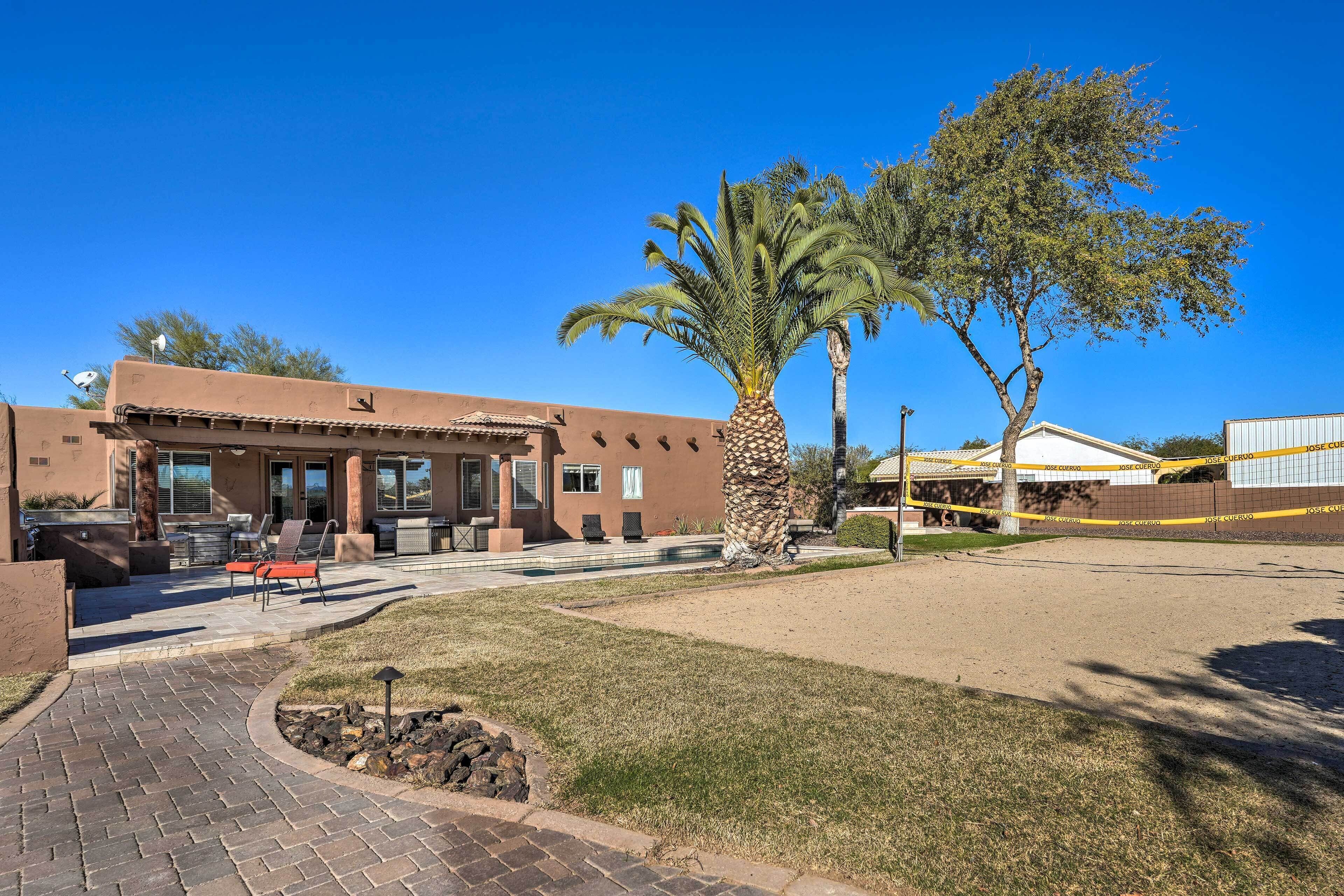 A building with a patio area, outdoor seating, and a palm tree.
