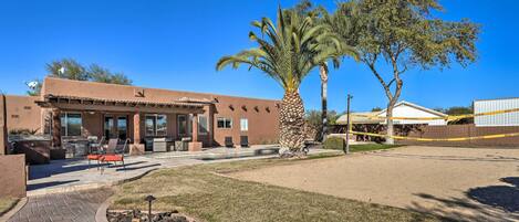 A building with a patio area, outdoor seating, and a palm tree.