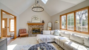 Amplia sala de estar con chimenea, un ventanal grande, un sillón de cuero y un sofá modular.