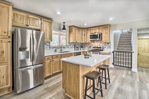 Una cocina moderna con armarios de madera, electrodomésticos de acero inoxidable y una isla central con taburetes.