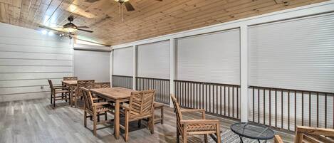A covered patio with a wooden table and chairs, a ceiling fan, and a view of the street.